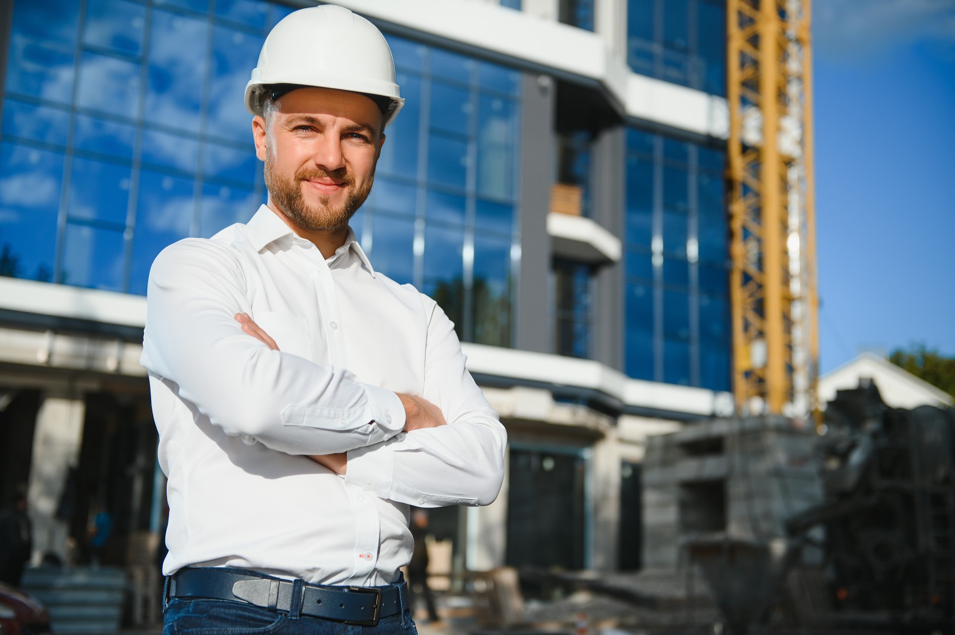 Portrait of man engineer at building site. Male construction manager wearing white helmet and yellow safety vest